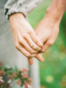 Up Close Portrait of Couple Holding Hands with emphasis on the engagement ring