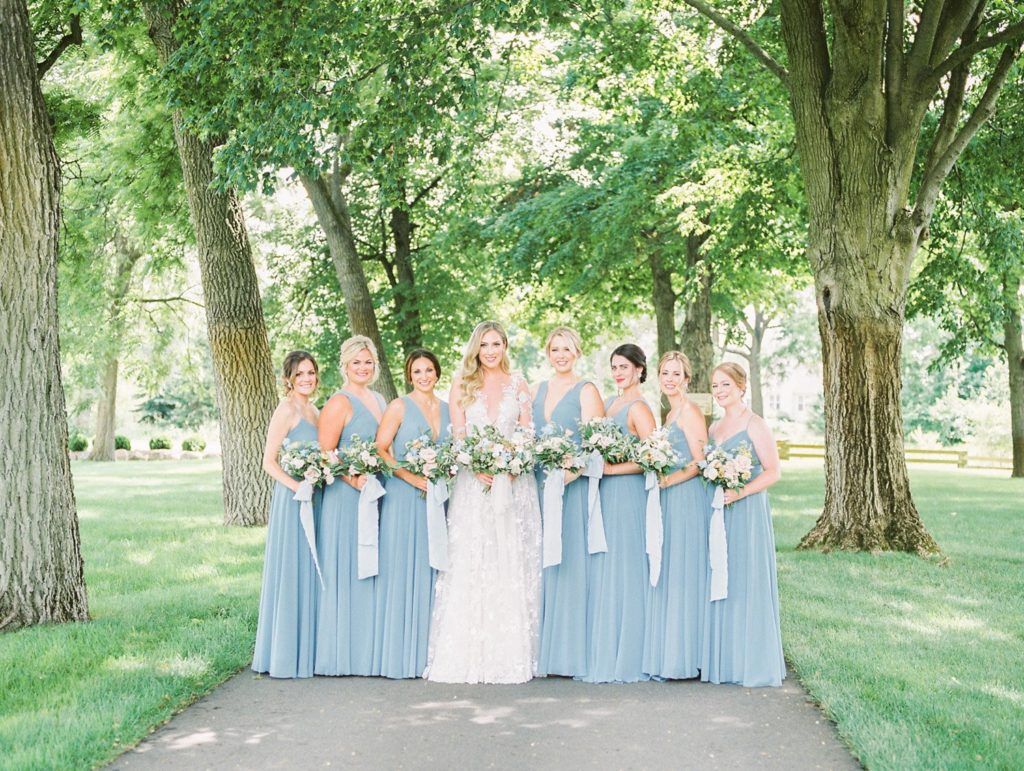 Wedding Party Bridal Portraits of Bride in a Lace Galia Lahav wedding gown and bridesmaids in soft baby blue gowns all holding bouquets with baby blue silk ribbons at Zingerman's Cornman Farms Wedding