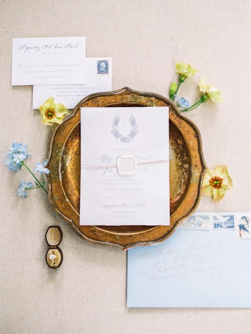 Simple yet Elegant Calligraphy Invitation Suite with a square, white wax seal, blue envelope with gold lettering and vintage stampsat a Zingerman's Cornman Farms Wedding Venue
