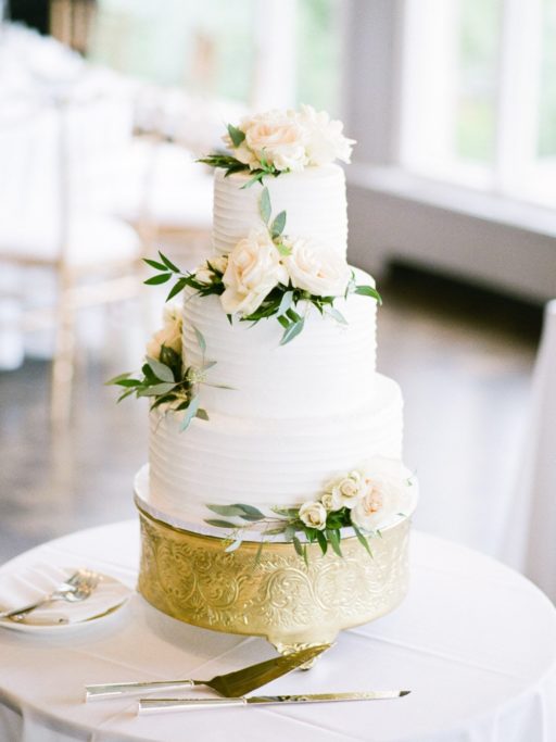 Three Tier White Wedding Cake with white and green flowers on a gold cake stand at a Grosse Pointe War Memorial Wedding
