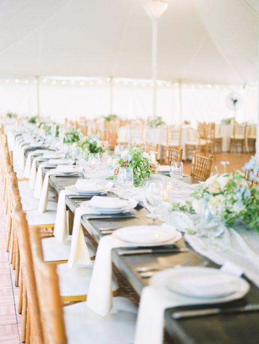 Soft blue toned Wedding Reception Tablescape with white plates and soft florals under a white tent at Zingerman Cornman Farms Wedding Venue