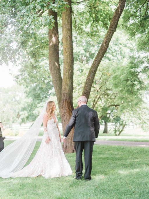 Bride in white, lace long sleeve Galia Lahav dress approaching her dad for a first look at a Zingermans Cornman Farms Wedding
